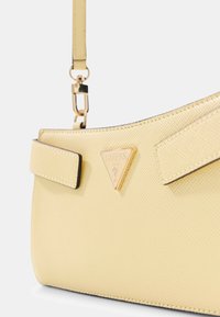 Borsa gialla con texture, con logo dorato triangolare, due cinturini laterali e finitura liscia, che mette in risalto la forma strutturata e le linee pulite.