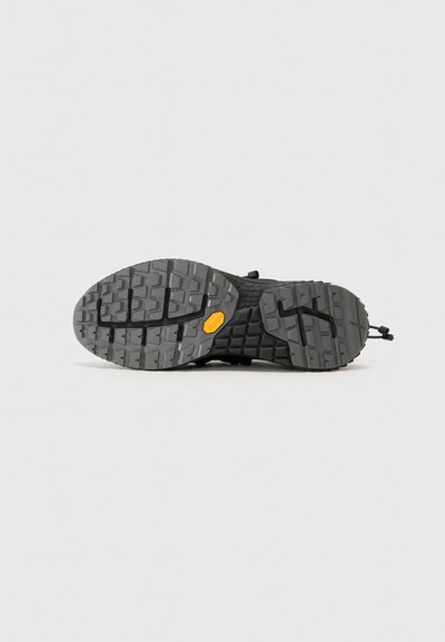 Black hiking shoe sole with a textured tread pattern for grip, featuring a Vibram logo and contrasting yellow accent.