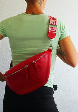 Rote Leder-Crossbody-Tasche mit zwei Reißverschlussfächern, glatter Textur und einem abnehmbaren Tragegurt mit auffälligem Logo-Muster.
