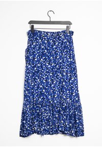 Jupe en tissu léger à imprimé floral bleu avec un ourlet festonné, présentant des motifs de feuilles noir et blanc, suspendue sur un cintre noir.