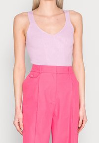 Ljus rosa ribbad linne med V-ringning och breda remmar, parat med höga klackar i stark rosa med knapppdetalj.