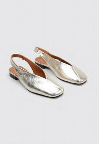 Zapatos slingback metálico plateados con punta cuadrada, tacón plano y textura suave. Presentan un diseño minimalista y un talón abierto para mayor transpirabilidad.