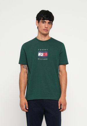 Zelené bavlnené tričko s malou multicolor grafikou so textom "TOMMY" a "1985 HILFIGER" v strede. Okrúhly výstrih a krátke rukávy.