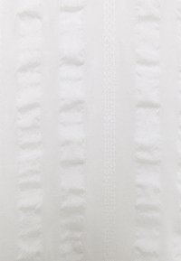 Tecido branco com riscas verticais, apresentando uma textura suave e franzida em algumas áreas, criando um contraste de padrões num material leve.