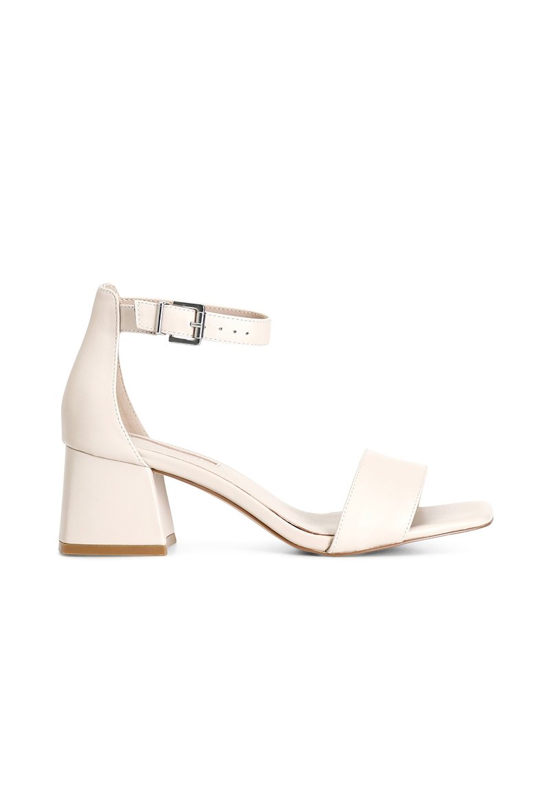 Beiga läder sandaler med blockklack har ett brett tåband och justerbart ankelsband med en silverspänne. Slät yta och minimalistisk design.