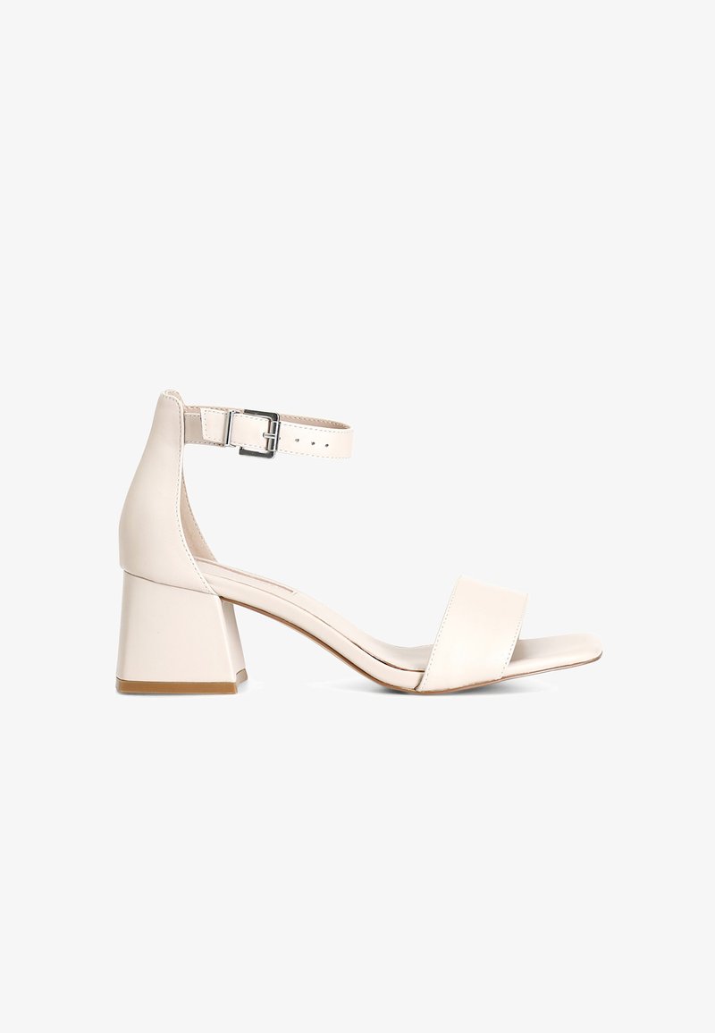 Beiga läder sandaler med blockklack har ett brett tåband och justerbart ankelsband med en silverspänne. Slät yta och minimalistisk design.