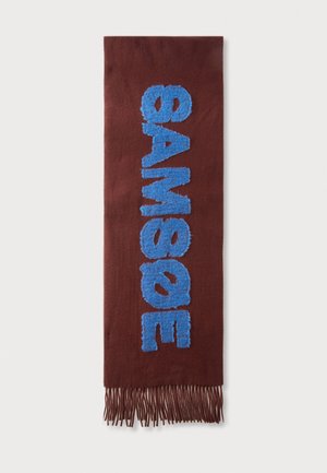Écharpe marron avec des lettres bleues duveteuses texturées épelant "GAMBAOE" verticalement et des bords à franges en bas.