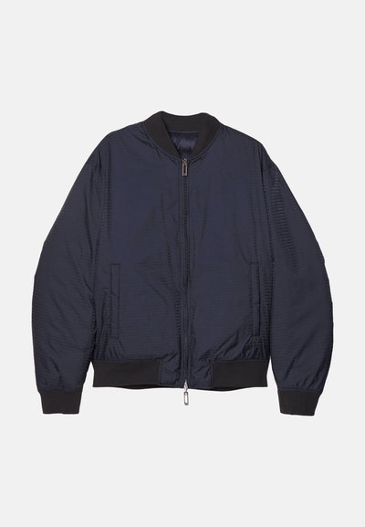Marinblå bomberjacka med dragkedja fram, ribbad krage och cuffs, texturerad tyg och två sidofickor. Designad med en avslappnad passform.
