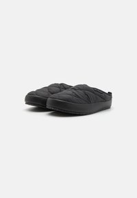 Czarne pikowane kapcie z gładką powierzchnią i gumową podeszwą. Bez widocznych elementów metalowych ani logo, zaprojektowane dla komfortu i łatwości noszenia.