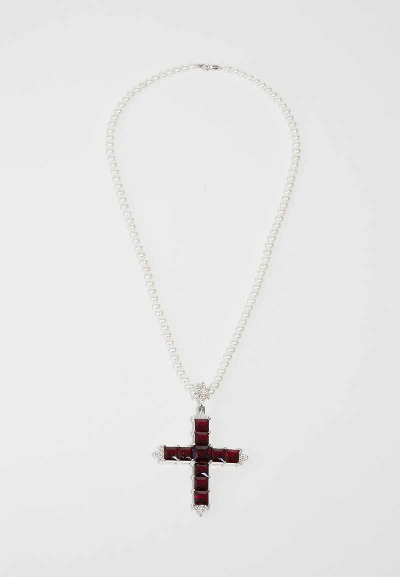 Collier de perles avec une grande pendentif en croix présentant des pierres précieuses rouges carrées et de petites pierres claires aux bords sur un fond blanc.