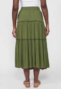 Falda larga plisada de color verde oliva con una cintura elástica. La tela parece suave y texturizada, con detalles de volantes en las costuras.