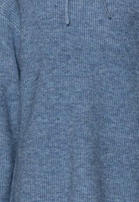 Blauwe gebreide trui met een geribd textuurpatroon, voorzien van een eenvoudig ontwerp en een klein trekkoordje bij de halslijn.