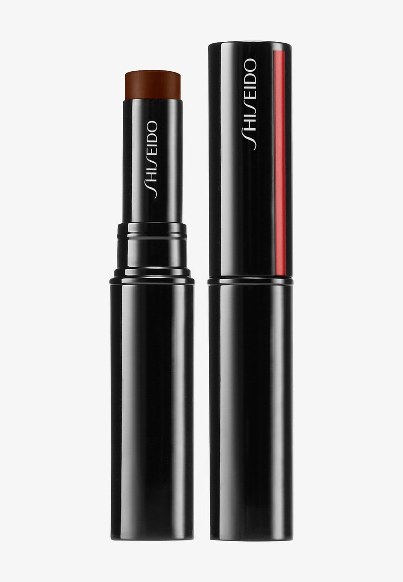 Bastoncino cosmetico nero con una cima arrotondata e un prodotto marrone intenso. Presenta una superficie lucida, dettagli in argento e il logo del marchio in bianco.