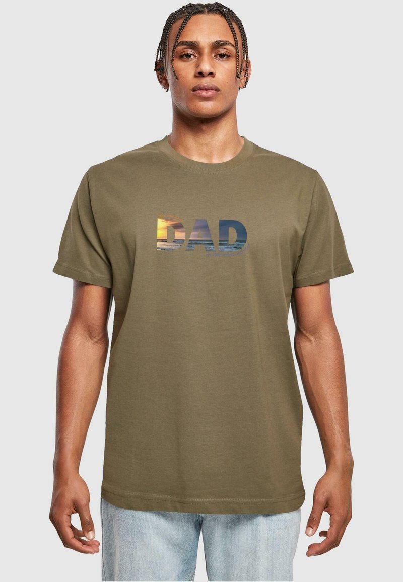 Oliven grøn bomulds t-shirt med ordet "DAD" og et sunset- og havmotiv på forsiden. Korte ærmer og rund hals.