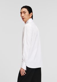 Witte langemouwen blouse van gladde stof, met een klassiek kraag en knopenmanchetten, met een rechte zoom en een minimalistisch ontwerp.