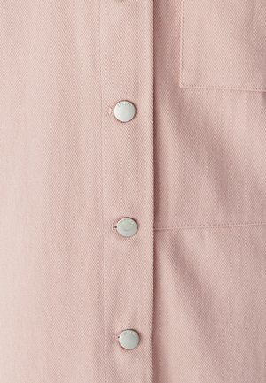 Šviesiai rožinė audinio medžiaga su tekstūruotu žuvelių kaulo raštu, priekyje penki sidabriniai spaudės mygtukai ir viena krūtinės kišenė.