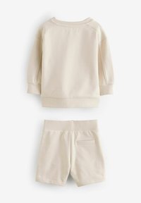 Beige bomulds sweatshirt med ribbestrikket halsudskæring og ærmer, parret med beige shorts med flad talje og en lille baglomme.