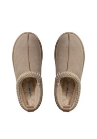 Beige indoor slippers made of soft suede with a plush lining, feature a textured braided trim and heel tab for easy wear.