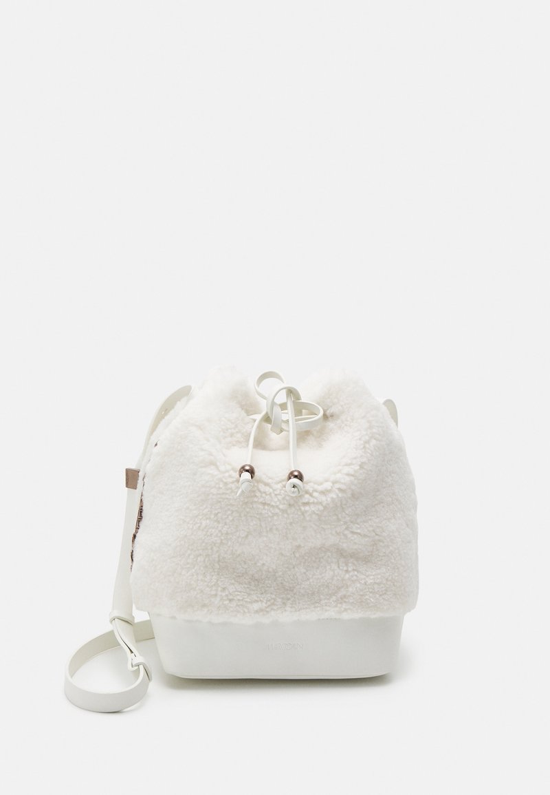 Sac seau blanc en tissu doux et duveteux avec fermeture à cordon, base lisse et solide, et bandoulière réglable.