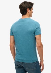 Teal T-shirt met korte mouwen in een zachte, textuurstof met een ronde hals en een rechte zoom, gecombineerd met denim jeans.