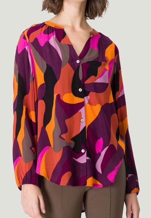 Blusa colorida abotonada de tela ligera. Presenta un escote en V, mangas largas con puños elásticos y formas abstractas en púrpura, naranja y rosa.