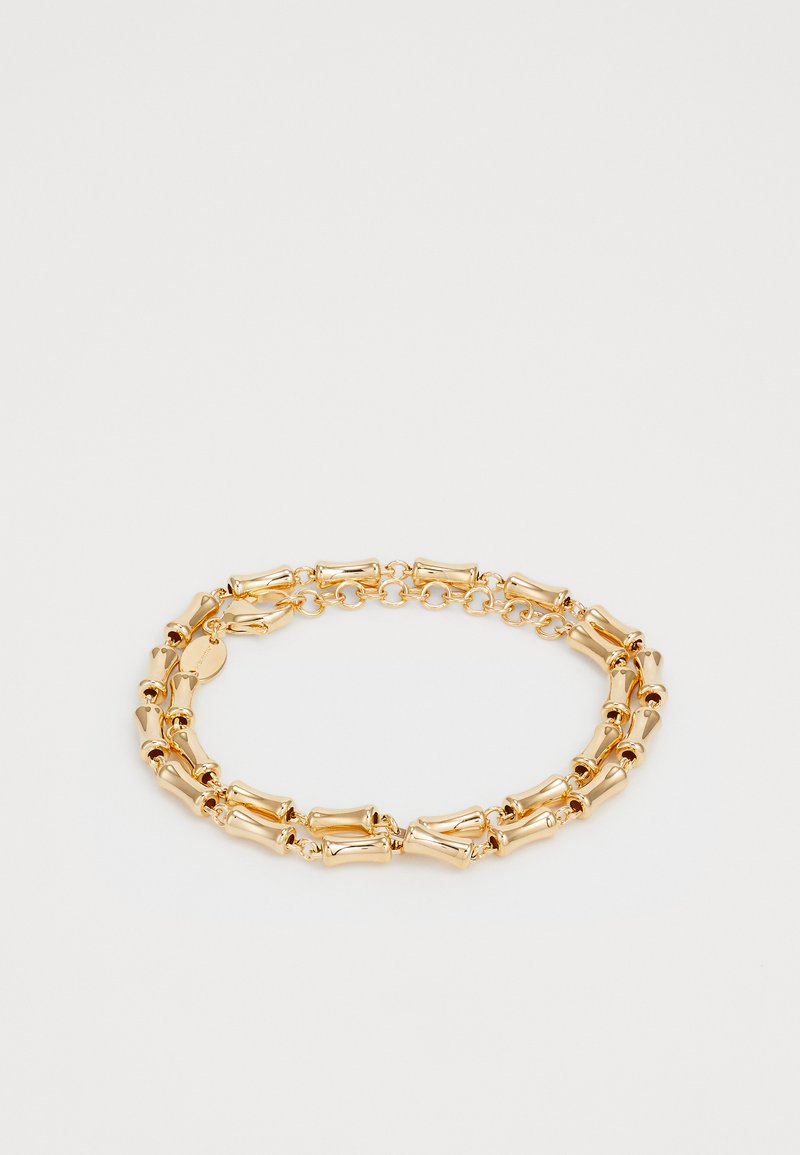 Dubbele laag gouden kettingarmband met buisvormige schakels en een karabijnsluiting op een witte achtergrond.