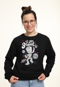 Sudadera negra con un gráfico de un personaje de dibujos animados y el texto "Yo soy Groot", rodeado de planetas y estrellas coloridas.