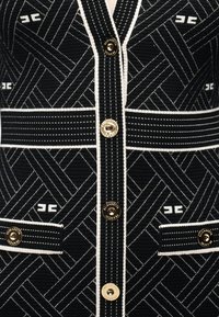 Υφάσμα με ασπρόμαυρο σχέδιο και χρυσά κουμπιά χαραγμένα με τη λέξη "Elisabetta Franchi" και μικρές τσέπες με εμπρόσθιο καπάκι.