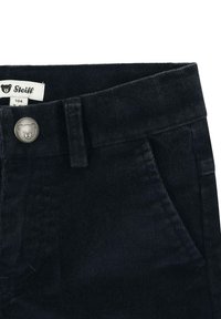 Pantaloni di velluto a coste blu scuro con una finitura testurizzata, passante per cintura, tasca anteriore e un dettaglio in metallo a forma di orso argentato sul cinturino.
