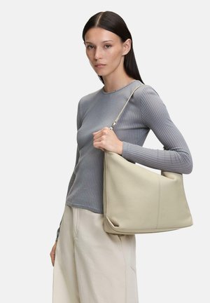 Beige leather handbag with soft, structured design, featuring a long strap, smooth texture, and side accents. Worn over the shoulder.