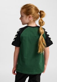 Grön bomulls-t-shirt med svarta ärmar, med enfärgad design och vita detaljer på ärmarna. Rak passform med rundad halsringning.