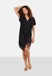 Vestido de cobertura de encaje negro con escote en V, mangas cortas y dobladillo con flecos. La tela texturizada añade un aspecto de capas. Ajuste cómodo.