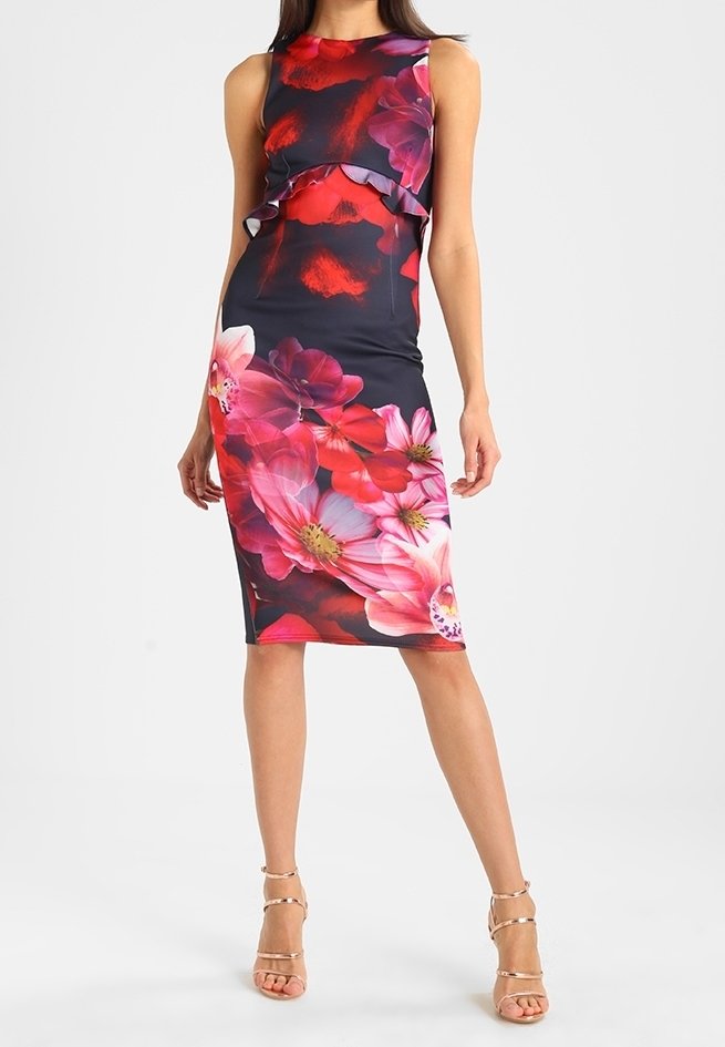 Abito nero senza maniche, lungo fino al ginocchio, con stampa floreale in rosso e rosa e dettagli a volants sul petto, abbinato a tacchi nudi con cinghie.