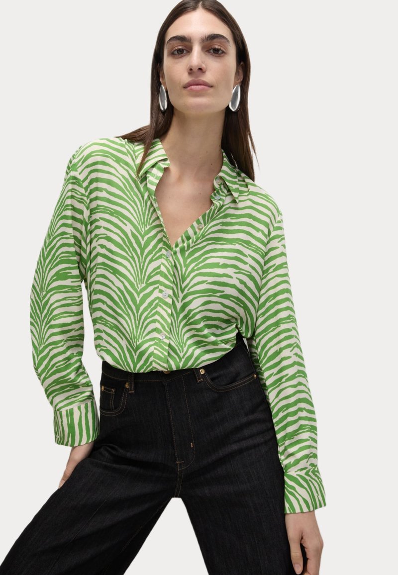 Groen en wit gestreepte button-up shirt met lange mouwen, voorzien van een kraag en een ontspannen pasvorm, gecombineerd met donkere spijkerbroek.