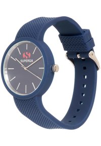 Reloj de silicona azul con esfera redonda, acentos plateados, correa texturizada y un dial transparente que muestra marcadores de hora blancos y un logo rojo.