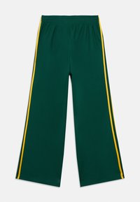 Grønne treningsbukser laget av teksturert stoff, med løs passform, elastisk midjebånd og gule striper på siden.