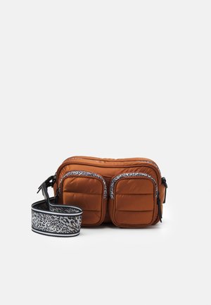 Sac bandoulière matelassé marron avec deux poches avant et une sangle large amovible avec imprimé animal noir et blanc.