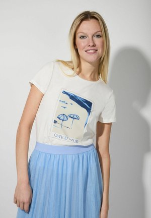 White T-shirt with a blue beach graphic, paired with a light blue tulle skirt featuring a waistband. Plain background.