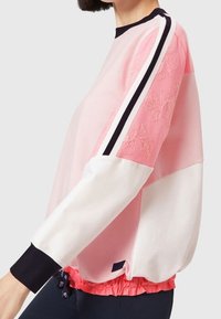 Sweat-shirt rose et blanc mélangé avec une texture florale sur une manche, poignet côtelé et ourlet élastique. Comprend des rayures noires contrastantes.