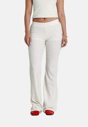 Weiße, gerippte, ausladende Hosen mit einem dehnbaren Bund, kombiniert mit einem passenden, cropped Oberteil und roten Schuhen, die eine dezente Logodetaillierung aufweisen.