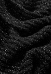 Crni džemper s tkaninom koja ima strukturiranu, gustu pletenicu. Sadrži bijele točkice koje su utkane kroz cijelu tkaninu, stvarajući kontrast naspram tamne pozadine.