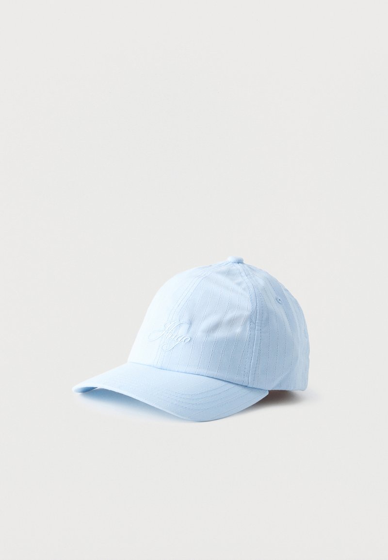 Casquette de baseball bleu clair avec des fines rayures verticales et un texte en cursive brodé sur le devant, posée sur un fond clair uni.