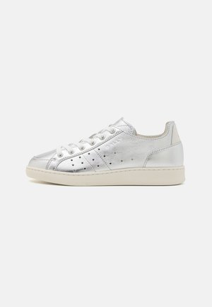 Silver metallic sneakers with a smooth texture, rounded toe, lace-up design, and perforated detailing on the sides. Cream-tone sole.