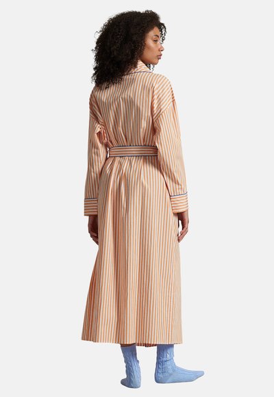 Pasiasty szlafrok w pomarańczowo-białe paski, wykonany z lekkiego materiału, z długimi rękawami, paskiem w talii oraz dopasowanymi niebieskimi prążkowanymi skarpetkami.