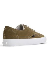Brune semsket lavtoppsneakers med hvite gummisåler og kontrasterende snørebånd. Har sydd detaljer og en liten merkeetikett på siden.