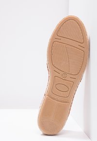 Semelle en caoutchouc beige avec des motifs texturés et des détails en relief ; "FABRIQUÉ EN ESPAGNE" et taille 37 imprimés à la surface.
