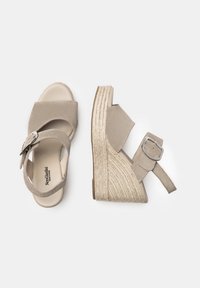 Beige wedge sandals with a textured fabric upper, adjustable ankle strap, and woven jute midsole. Rounded toe and flat rubber outsole.