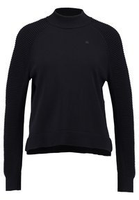 Svart tröja med hög hals, texturerade ribbade ärmar och en avslappnad passform. Har minimal logotyp på bröstet och en enhetlig design.