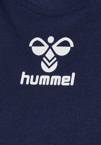 Navyblauwe katoenen T-shirt met een wit logo met ronde vormen en bladvormen, centaal geplaatst boven het woord "hummel."