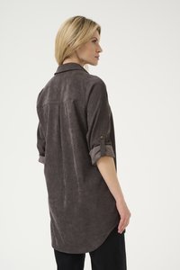 Chemise à boutons en velours côtelé gris foncé. Manches longues pouvant être retroussées et sécurisées. Dotée d'un pli au dos pour un ajustement décontracté.